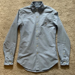 Blå Ralph Lauren skjorta - Hej, säljer en ljusblå buttondown Ralph Lauren skjorta i XS slim fit. Den är perfekt nu till sommaren till både vardagsbruk och mer formella tillfällen. Skjortan är väldigt sparsamt använd och har inga defekter. Priset är ej hugget i sten, kom med prisförslag. // Mvh Edvard