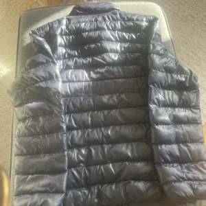 Svart pufferjacka från Polo Ralph Lauren - The Beaton Packable Glossed Jacket                                              Säljer en snygg svart pufferjacka från Polo Ralph Lauren. Jackan har en dragkedja framtill och är quiltad för extra värme. Perfekt för kyligare dagar med stilrena design. Vattenavvisande. 