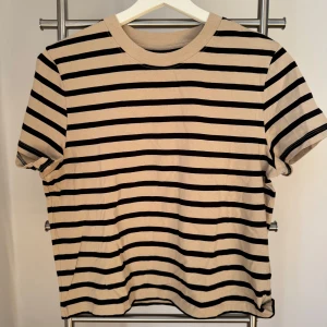 Ny, oanvänd, beige svart randig T-shirt från Lindex!  - Ny, oanvänd, beige svart randig T-shirt från Lindex i storlek M med prislappen kvar. Nypris 199kr