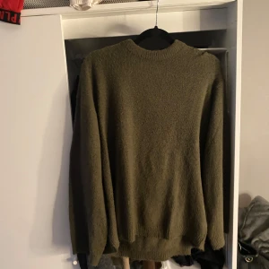 Olivgrön tröja från 157 - Säljer en olivgrön tröja från 157 i storlek M. Tröjan har en enkel design med rund hals och långa ärmar. Perfekt för kyligare dagar.