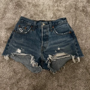 Levi’s jeansshorts - Ett par blåa jeans shorts från Levi’s som är midwaist och perfekta i längd bak och fram. Storleksmässigt är de ganska små och jag som är en S får inte ihop dem. 