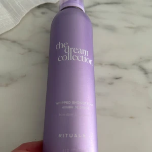 Lila duschmousse från Rituals - Säljer en lila flaska duschmousse från Rituals, 'The Dream Collection'. Flaskan har en elegant design med en mjuk lila färg och vit text. Perfekt för en lyxig duschupplevelse med en doft av blue daisy.