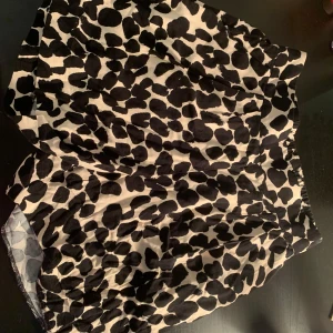 Svartvit leopardmönstrad shorts  - Trendiga shorts med svartvitt leopardmönster. Perfekt för att ge din outfit en djärv touch. Shortsen har en elastisk midja för extra komfort.