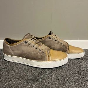Bruna sneakers från Lanvin - Snygga sneakers från Lanvin i en kombination av mocka och skinn. Skorna har en beige och brun färg med snörning och en vit sula, skorna är i skick 7-10✅ 