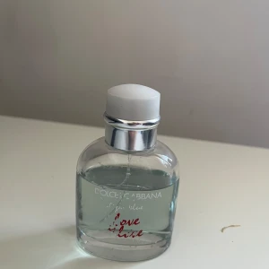 Dolce & Gabbana Light Blue Love is Love - Säljer en fräsch och modern parfym från Dolce & Gabbana, Light Blue Love is Love. Flaskan är genomskinlig med en vit kork och har en stilren design med röd text. Perfekt för den som älskar en lätt och uppfriskande doft.