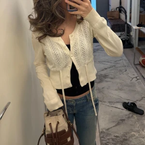 Vit stickad kofta med knappar - Säljer en söt vit stickad kofta med fina detaljer och knappar framtill. Koftan har långa ärmar och en croppad passform som ger en trendig look. Perfekt för att lägga till en touch av elegans till din outfit. Storlek Xs men passar även S❤️💕