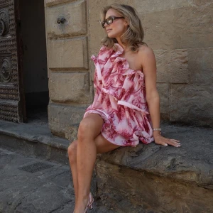 Slutsåld klänning lojsan Wallin  - Säljer en fantastisk rosa one-shoulder klänning med blommigt mönster och volangdetaljer. Från Lovisa wallins nya kollektion med NA-KD klänningen är helt slutsåld!