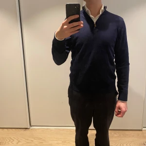 Stenströms half zip - Säljer en marinblå långärmad tröja i 100% merinoull från Stenstrlns. Tröjan har en halv dragkedja vid halsen och en klassisk, stilren design. Perfekt för lager-på-lager och snygg till både skjorta och t-shirt. Litet hål i ena armen, därav priset.