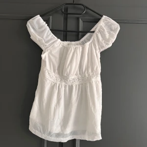 Vit blus med spetsdetaljer - Söt vit blus med puffiga korta ärmar och vackra spetsdetaljer vid midjan och ärmslut. Är från shein därav priset 