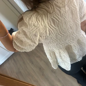 Vit topp med knytning - En fin topp med knytning fram med textur i tyget. Andvänd ett fåtal tillfällen och ser helt ny ut