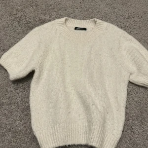 Vit stickad kortärmad från Gina Tricot - Mysig vit stickad tröja från Gina Tricot med korta ärmar och rund halsringning. Tröjan har en klassisk, enkel design och är perfekt för våren! Skriv hälst innan köp! Endast använd fåtal gånger så den är i mycket bra skick. Är i storlek M men passar även mindre storlekar (funkar på mig som har runt xs) 