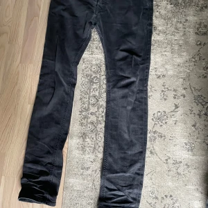Diesel jeans - Säljer ett par svarta Diesel Larkee jeans med klassisk femficksdesign och diskret Diesel-logga vid myntfickan. Jeansen har raka ben och normal passform, perfekta för en stilren look.