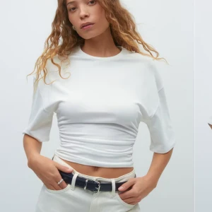 Vit topp - Säljer en vit croppad t-shirt från gina med korta ärmar och rynkade detaljer längs sidorna. Den är nyköpt och använt en gång, tänkte lämna tillbaka den men har tagit av prislappen tyvärr. Storlek XS