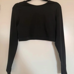 Svart croppad topp med snörning från SHEIN - Säljer en svart croppad långärmad topp från SHEIN. Toppen har snygga snörningsdetaljer i ryggen som ger en cool look. Perfekt till gymmet