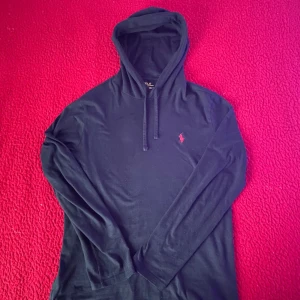 Svart hoodie från Ralph Lauren - Säljer en stilren svart hoodie från Ralph Lauren. Den har en klassisk design med en liten röd logga på bröstet. Perfekt för både vardag och chill. Den är i ny skick och superbekväm! Den är tunn och i 100% bomull❤️