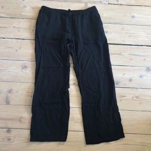 Svarta mjukisbyxor från H&M - Svarta linnebyxor från H&M med resår i midjan. Byxorna har en rak och loose passform, perfekta för en avslappnad stil. Tillverkade i mjukt bomullsmaterial som känns skönt mot huden. De har ett litet hål längst ner på ena byxan.💗 använd inte köp nu, kontakta mig först💗