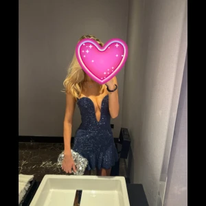 Blå glittrig Oh Polly  - Använd bara en gång, helt ny. Supersnygg blå miniklänning med glittriga paljetter och halterneck. Djup v-ringning och volangkant nertill ger en festlig look. Perfekt för dig som vill sticka ut! Klänningen har en tight passform och är kort. 