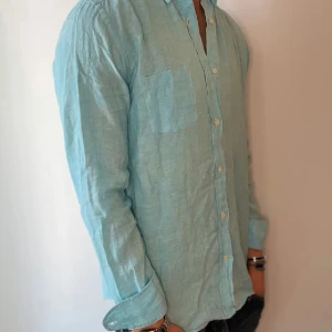 Ljusblå linneskjorta - Säljer denna riktigt snygga linneskjortan från uniqlo. Skön passform och perfekt till sommarn 