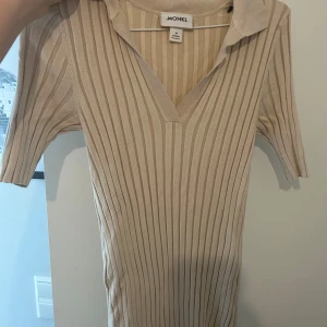 Beige ribbad klänning med krage från Monki - Från Monki med v-ringning och krage. Klänningen har korta ärmar och är figurnära med stretchigt material. 
