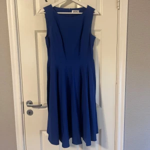 Blå ärmlös klänning med vidd i kjolen - Säljer en stilren blå klänning med breda axelband och markerad midja. Klänningen har en vacker, utsvängd kjol och är helt ärmlös. Perfekt för dig som gillar enkel men elegant stil.