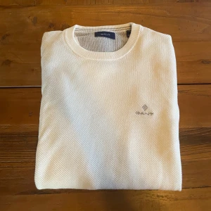 Vit stickad tröja från GANT - Säljer en stilren vit stickad tröja från GANT med diskret logga broderad på bröstet. Tröjan har rund halsringning och långa ärmar. Perfekt för en clean och klassisk look. Nypris: 1199kr