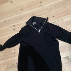 Svart ribbad tröja med dragkedja från H&M - Svart långärmad tröja från H&M med ribbad struktur och hög krage med dragkedja. Helt ny aldrig använt. Köpte 599 säljer för 120 kr