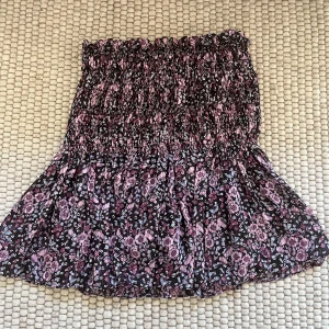 Blommigt sett från Zara - Supersöt croppad blus med volangkjol från ZARA i svart med lila och rosa blommigt mönster. Går bra att köpa plaggen enskilt också! Har tyvärr ingen bild på blusen då den är lite för kort på mig. 400 för båda