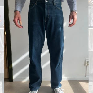 Blå jeansbyxor från Weekday - Säljer ett par klassiska blå jeans från Weekday i modellen Galaxy Loose Straight Jeans. Byxorna har raka ben och normal passform, tillverkade i denim med fem fickor och gylf med dragkedja.
