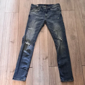 Jack and Jones jeans med slitningar  - Säljer dessa snygga Jack and Jones jeans med slitningar som är ett perfekt plagg när man ska chilla eller ska ut med vänner. De är W33 L34. Kontakta vid funderingar!