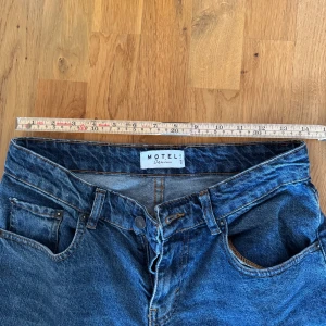 Blå wide leg jeans från Motel Denim - Säljer ett par blå jeans från Motel Denim med hög midja och breda ben. Klassisk femficksmodell med raka, vida ben och råa kanter nertill. Perfekta för en avslappnad och trendig look.