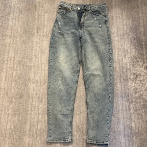 Blå wide jeans från H&M, storlek 38 - Säljer ett par blåa wide jeans från H&M i storlek 38. Jeansen har hög midja, klassisk femficksdesign och raka, vida ben. Materialet är jeans med snygg tvättad look och slitningar för en cool vibe.