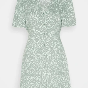 Grön sommar klänning  - Grön klänning med vita prickar, v-ringning och korta ärmar. Klänningen har knappar framtill och en knytdetalj i midjan. Säljes på grund av köpt fel storlek. Endast använd vid ett tillfälle.