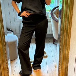Svarta kostymbyxor med raka ben - Säljer ett par svarta kostymbyxor med normal passform och raka, lite vidare ben. Byxorna har hög midja och klassisk look med fickor i sidorna. Perfekta om du vill ha en clean och stilren vibe. Materialet känns mjukt och följsamt. Dom är i storlek 32 men jag har ofta S/M och dom passar mig bra men är dock sjukt långa. Lite slitna längst ner pga längden!