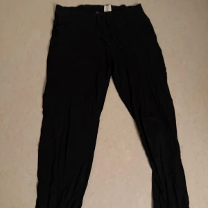 Svarta mjukisbyxor med snörning - Svarta mjukisbyxor med avslappnad passform och snörning i midjan. Perfekta för chill dagar eller när du vill vara bekväm. Tillverkade i mjukt material som känns skönt mot huden.