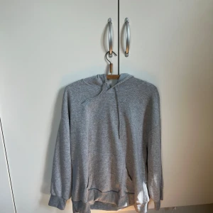 Grå hoodie med 8-ball print - Säljer en grå hoodie med huva och snörning. På ryggen finns ett stort svart 8-ball tryck. Aldrig använd .