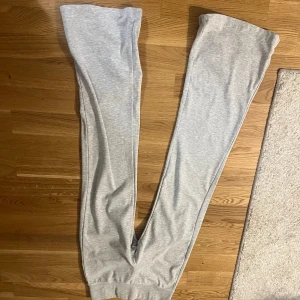 Grå mjukisbyxor från Bershka - Ljusgrå mjukisbyxor från Bershka med ribbade muddar vid bensluten. Byxorna har en avslappnad passform och är tillverkade i mjukt bomullsmaterial, perfekta för chill dagar eller när du vill vara extra bekväm. Jätte sköna men tycker att de blivit lite korta på mig🥰