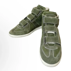 Maison Margiela sällsynta sneakers !! - Unika gröna sneakers i mocka med vita kontrastsömmar och breda kardborreband. Skorna har vit platt sula och textdetalj på sidan där det står ”Rental”. Rental byteder inte att det är hyres utan det är bara kollektionen av Margiela som hette så. Dm om du har fler frågor eller vill ha fler bilder !!
