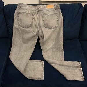 Grå jeans från Zara med rak passform - Snygga grå jeans från Zara i tvättad look. Klassisk femficksmodell med raka ben och normal passform. Jeansen har silverfärgade nitar och knapp, samt bälteshällor. Perfekta för en chill och stilren vibe. Storlek: Midja: 34 Längd: 32. Original Pris: 400 - 600kr