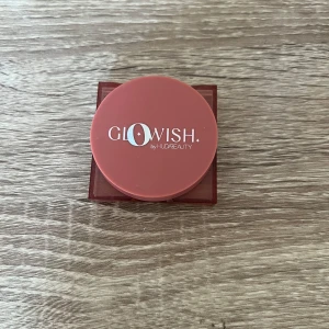 Glowish Cheeky Vegan Rouge Peach - Använd några få gånger, Glowish by Huda Beauty Cheeky Vegan Blush Powder i färgen 01 Healthy Peach. Kommer i en rund, persikofärgad dosa med spegel. Puderrouget har en marmorerad finish i en varm persikoton och är veganskt.