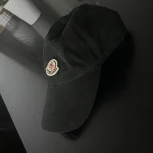 Moncler keps - Moncler keps som används en gång bara. Ligger och dammar bara i garderoben. Är i perfekt skick.   Storlek: No Size (justerbar)   Nypris: 2000 kr 