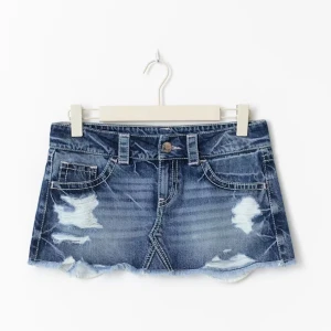 Blå jeanskjol med slitningar - Superkort jeanskjol i blå denim med slitna detaljer och fransig nederkant. Klassisk femficksmodell med bälteshällor och knappstängning framtill. Så så fin💕