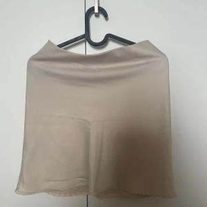 Beige satinliknande kjol från BikBok - Superfin beige kortkjol från BikBok i satinliknande material. Fint skick. 