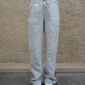 Beiga linnebyxor med snörning - Snygga och luftiga linnebyxor i beige med hög midja och dragsko i midjan. Byxorna har raka ben och sidfickor, perfekta för en chill och avslappnad stil. Materialet är linne vilket gör dem sköna och svala under varmare dagar. Har aldrig använt dom🥰