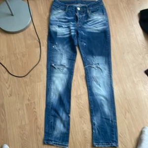 Dsquared2 slitna blå jeans herr kan senka priset om  det böhves  - Riktigt snygga blå jeans från Dsquared2 med slitna detaljer och distressed look. Jeansen har normal passform, klassisk femficksmodell och coola slitningar framtill. Tillverkade i bomull med Dsquared2-logga på bakfickan och knapp. Perfekta för en streetstyle vibe.