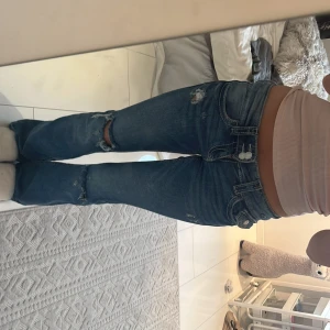 Blå bootcut jeans med slitningar - Snygga blå jeans med bootcut passform och slitna detaljer på knä och fickor. Jeansen har låg midja . Från Gina Young i storlek 146 tall 