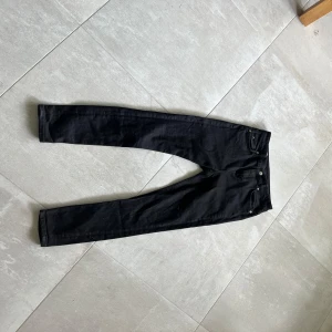 Svarta jeans från J.Lindeberg - Svarta skinny jeans från J.Lindeberg. Jeansen har silverfärgade detaljer och diskret logga på myntfickan. Snygg passform med smala ben och normal midja. Perfekta till sneakers eller boots. Nästan helt nya, inte trasiga eller slitna. Nypris ca 1400. Skriv om frågor. Byten är intressant.