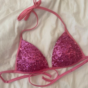 Rosa paljettbikini från Calzedonia - Superfin rosa bikiniöverdel från Calzedonia med glittriga paljetter över hela framsidan. Klassisk triangelmodell med knyt både i nacken och runt ryggen. Perfekt för dig som vill sticka ut på stranden eller vid poolen.💓💓 Skicket är som på bilden 