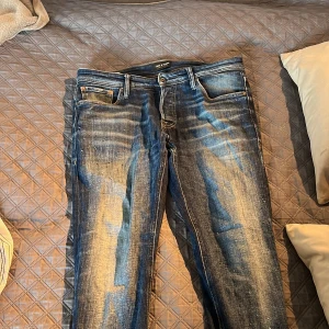 Blå jeans från Jack & Jones, 30/30 - Snygga blå jeans från Jack & Jones med klassisk femficksdesign och slitna detaljer framtill. Jeansen har normal passform och raka ben, tillverkade i tåligt denimtyg. Perfekta för en avslappnad och trendig look.