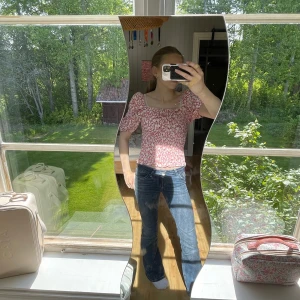 Blommig smockad topp från ONLY - Supersöt blommig topp från ONLY med smockad kropp och puffiga korta ärmar. Toppen har fyrkantig urringning och är i ljusa färger med rosa, vit, gul och lila i mönstret. Perfekt för dig som gillar romantisk och trendig stil.