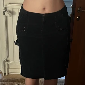 Mörkblå manchesterkjol med nitar - Navy kort kjol i manchester med coola nitar på fickorna och snygga detaljer på sidorna. Dragkedjan saknar handdtag men funkar ändå 